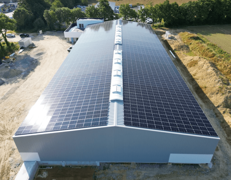 Vue aérienne d'un bâtiment industriel avec panneaux solaires sur le toit.