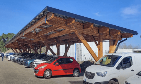 Abri en bois avec panneaux solaires à Laval Agglomération, abritant des voitures.