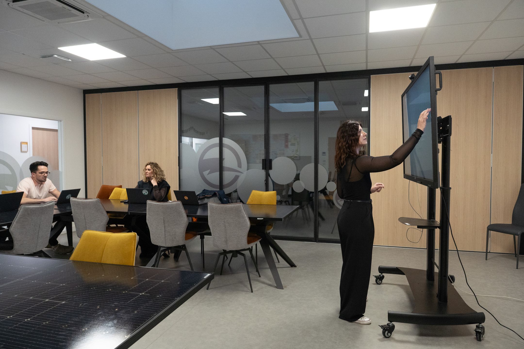 Équipe en réunion dans un bureau moderne avec écran interactif