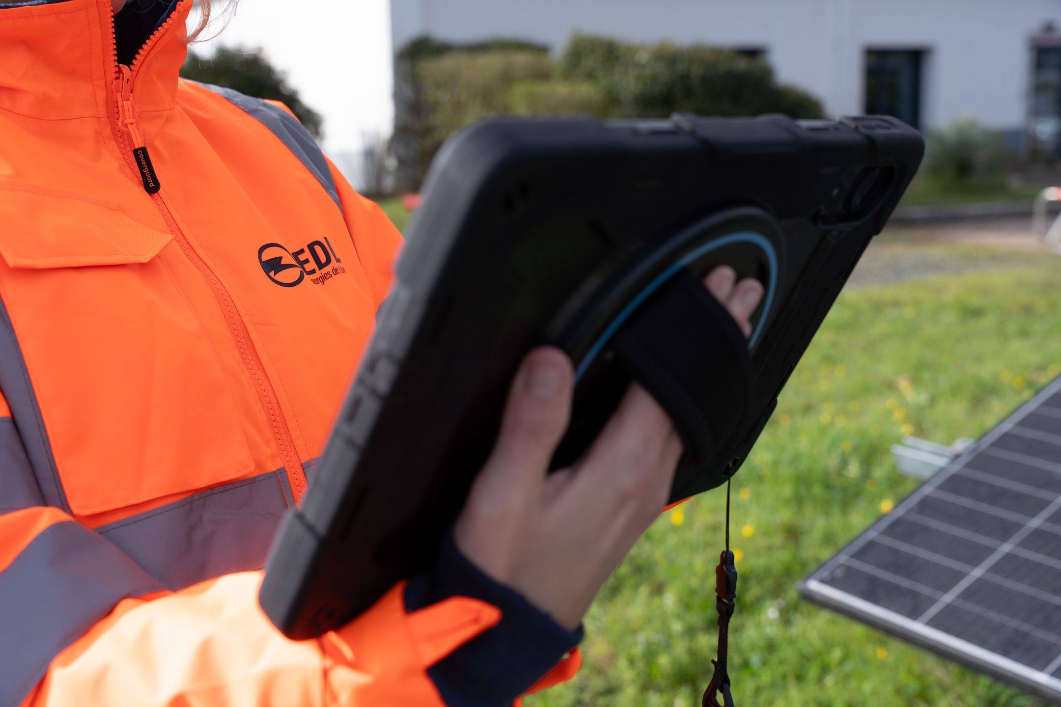 Employée EDI en tenue de travail avec une tablette, à côté de panneaux solaires.